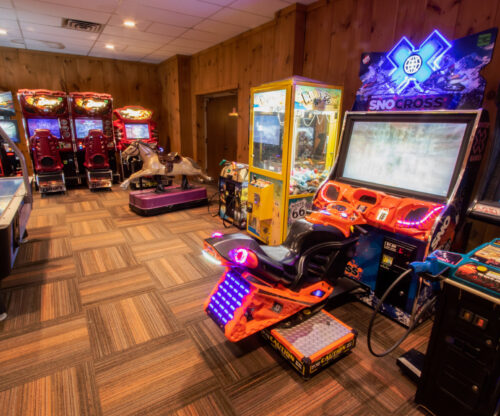 Game room with a claw machine, car games, and a coin-operated horse ride machine. 